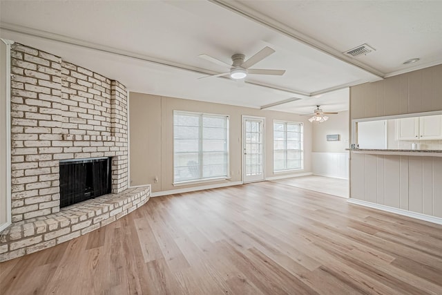 unfurnished living room featuring beamed ceiling, a brick fireplace, ceiling fan, and light hardwood / wood-style flooring