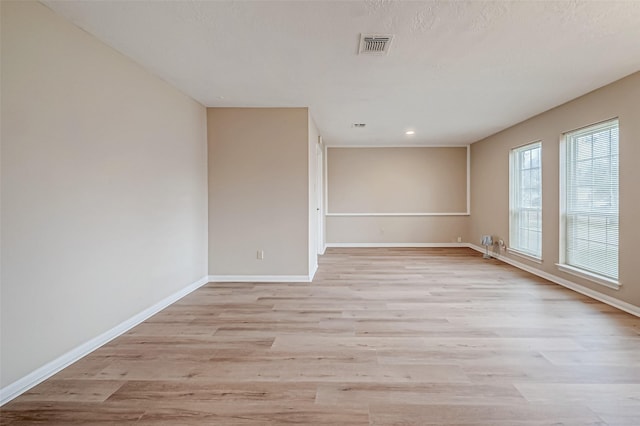 unfurnished room with light hardwood / wood-style flooring and a textured ceiling