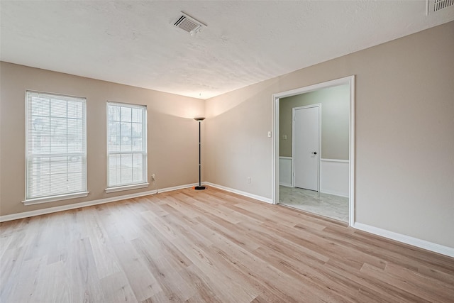 spare room featuring a textured ceiling and light wood-type flooring