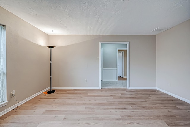 empty room featuring a textured ceiling and light wood-type flooring