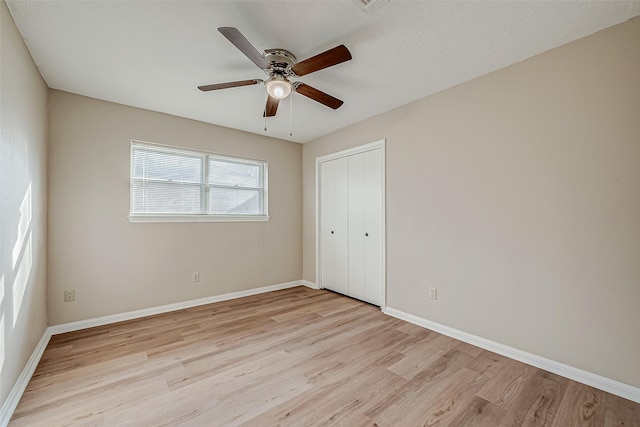 unfurnished bedroom featuring ceiling fan, light wood-type flooring, and a closet