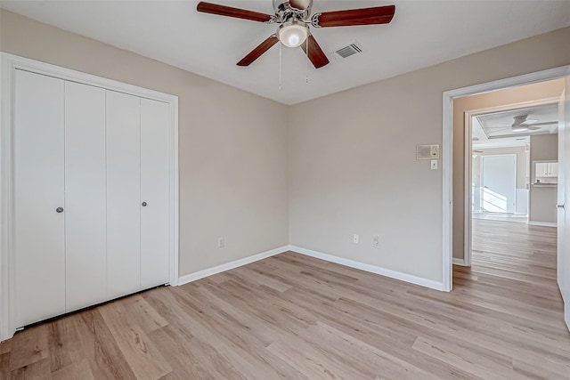 unfurnished bedroom with light hardwood / wood-style flooring, a closet, and ceiling fan