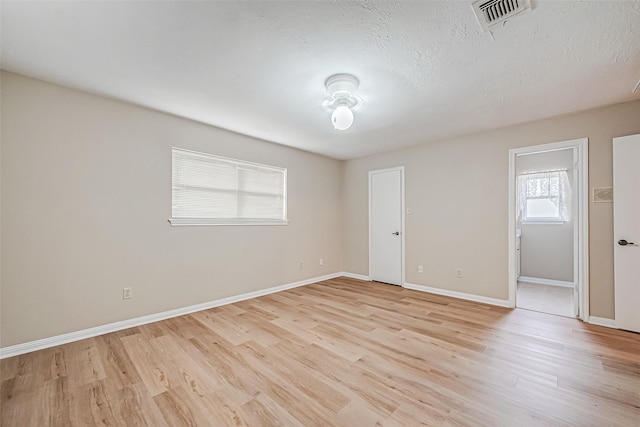 spare room featuring a textured ceiling and light hardwood / wood-style floors