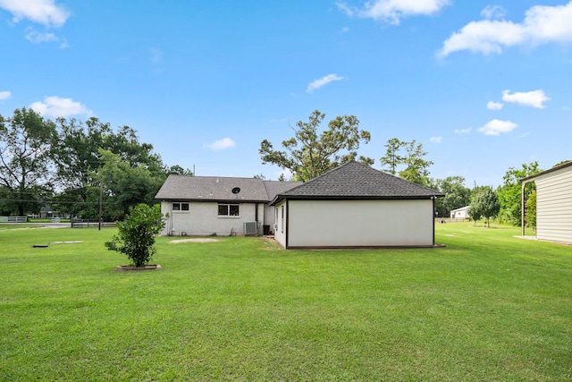 rear view of property featuring a yard and central air condition unit