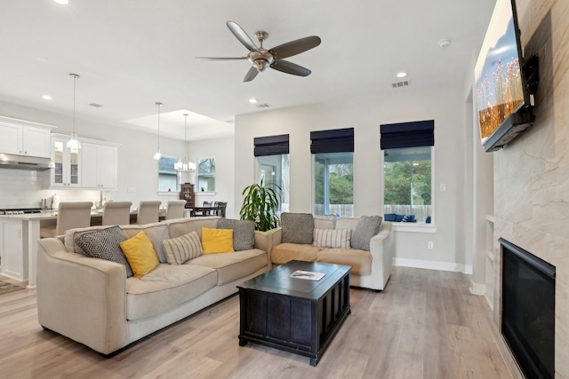 living room with ceiling fan with notable chandelier and light hardwood / wood-style floors