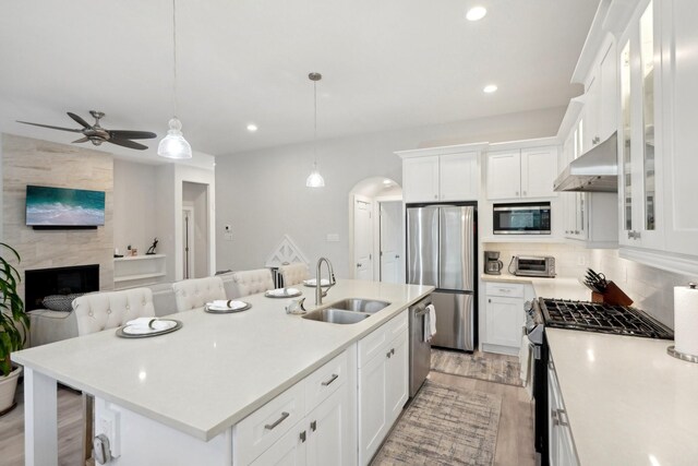 kitchen with stainless steel appliances, white cabinetry, sink, and a breakfast bar area