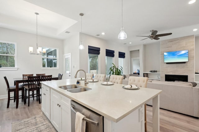 kitchen with white cabinetry, sink, hanging light fixtures, a kitchen island with sink, and stainless steel dishwasher