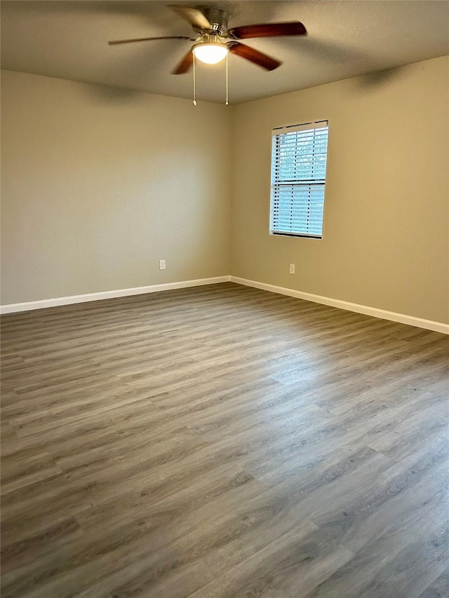 empty room with dark hardwood / wood-style floors and ceiling fan