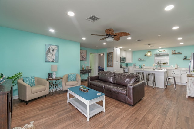 living room with sink, wood-type flooring, and ceiling fan