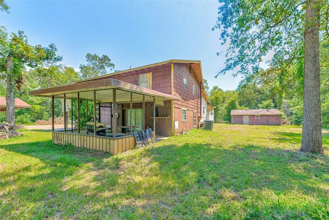 rear view of house featuring a yard, central air condition unit, and a storage unit