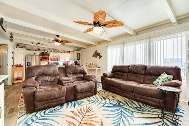 living room with ceiling fan, hardwood / wood-style floors, and vaulted ceiling with beams