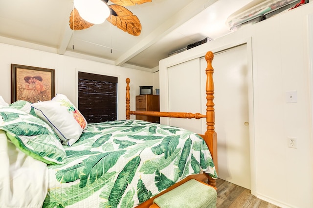 bedroom with ceiling fan, hardwood / wood-style flooring, and beamed ceiling