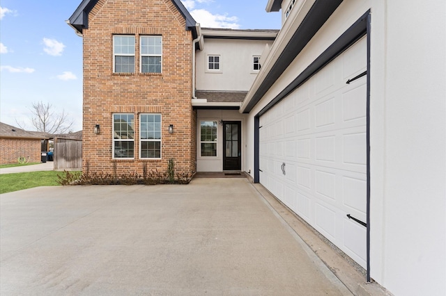 view of front of house with a garage, driveway, brick siding, and stucco siding