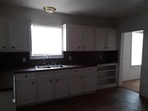 kitchen featuring dark countertops, white cabinetry, and a sink