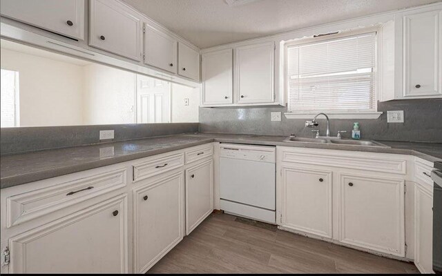 kitchen with light wood-style flooring, white dishwasher, white cabinets, and a sink