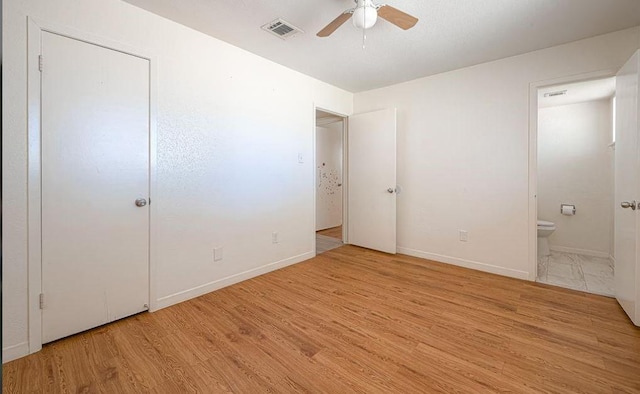 unfurnished bedroom featuring baseboards, visible vents, connected bathroom, ceiling fan, and wood finished floors