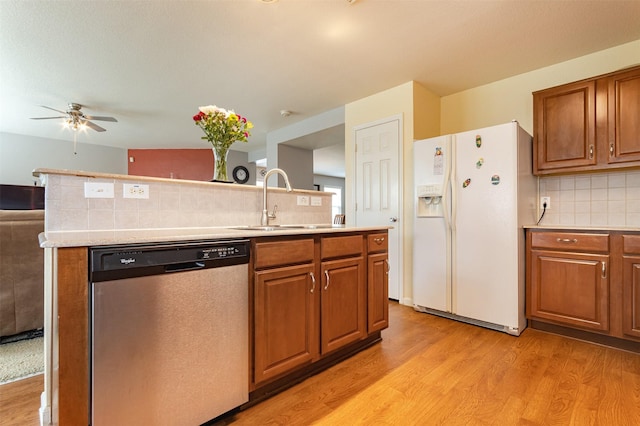 kitchen featuring sink, backsplash, white refrigerator with ice dispenser, stainless steel dishwasher, and light hardwood / wood-style floors