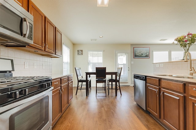 kitchen featuring stainless steel appliances, sink, backsplash, and light wood-type flooring