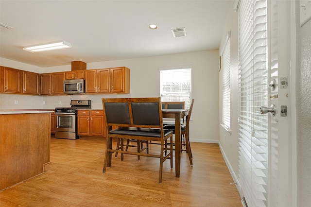 kitchen with appliances with stainless steel finishes and light hardwood / wood-style flooring