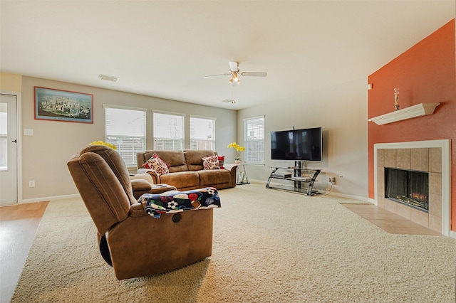 carpeted living room featuring a tiled fireplace and ceiling fan