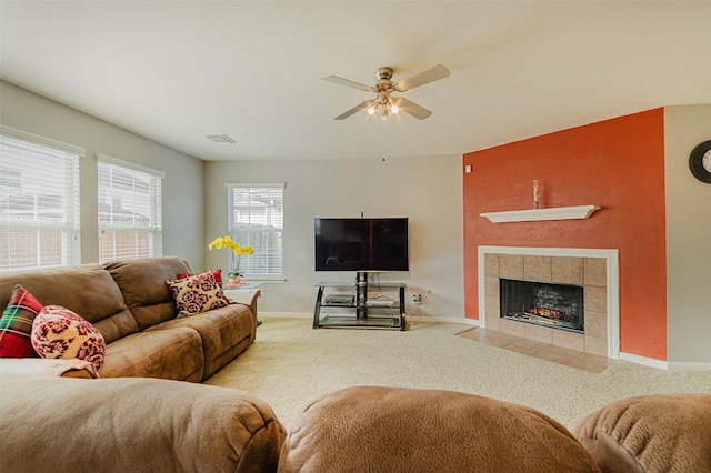 living room with ceiling fan, carpet flooring, and a tiled fireplace