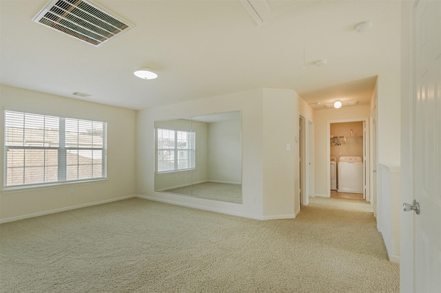 unfurnished room featuring light colored carpet and washing machine and clothes dryer