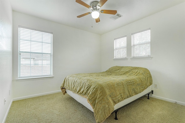 bedroom featuring multiple windows, light colored carpet, and ceiling fan