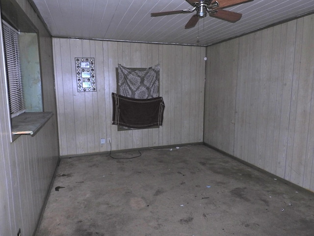 spare room featuring ceiling fan and wood walls