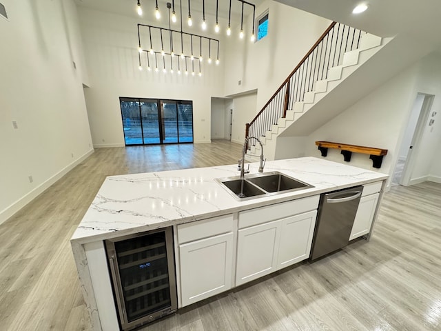 kitchen featuring pendant lighting, dishwasher, sink, white cabinets, and wine cooler