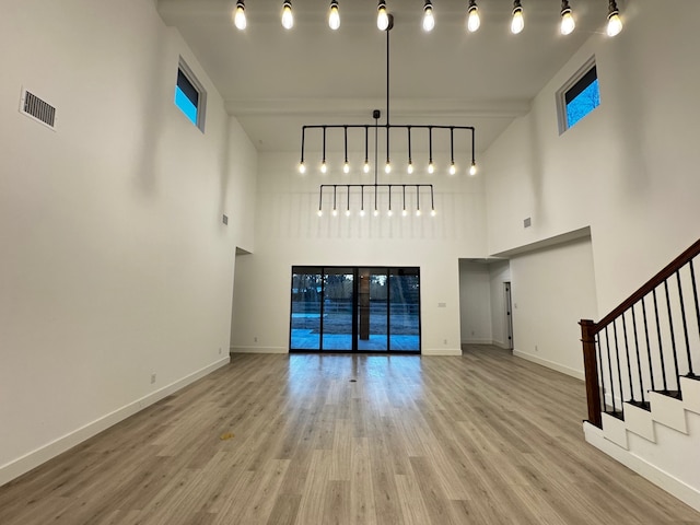 unfurnished living room with light hardwood / wood-style flooring and a high ceiling