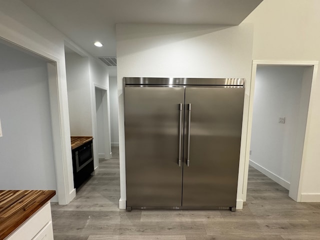 kitchen featuring built in fridge, white cabinetry, wooden counters, and light wood-type flooring