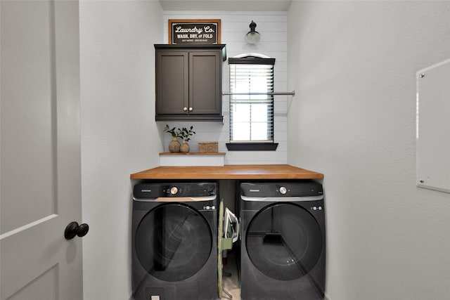 clothes washing area featuring cabinets and washer and clothes dryer