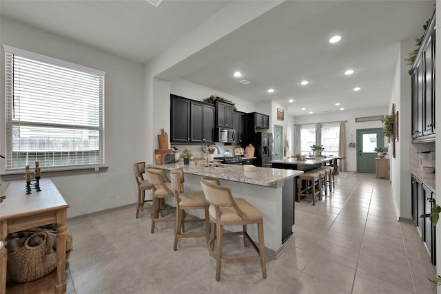 kitchen with stainless steel appliances, a kitchen breakfast bar, light stone counters, tasteful backsplash, and kitchen peninsula