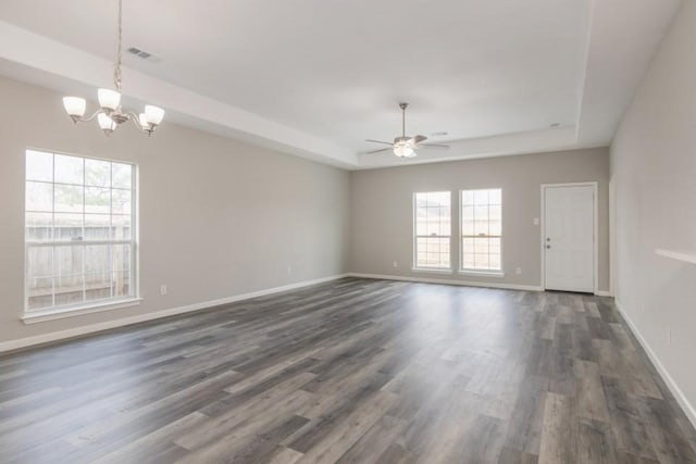 spare room featuring a tray ceiling, ceiling fan with notable chandelier, and dark hardwood / wood-style floors