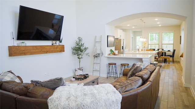 living room featuring a chandelier, sink, and light hardwood / wood-style flooring