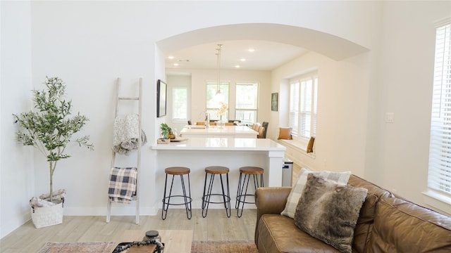 kitchen with sink, light hardwood / wood-style flooring, a breakfast bar area, hanging light fixtures, and kitchen peninsula