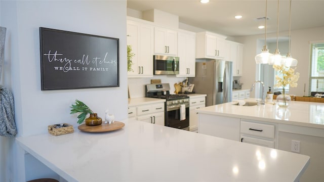 kitchen with sink, decorative light fixtures, a center island with sink, stainless steel appliances, and white cabinets