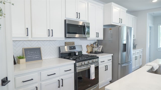 kitchen featuring decorative backsplash, white cabinets, and appliances with stainless steel finishes