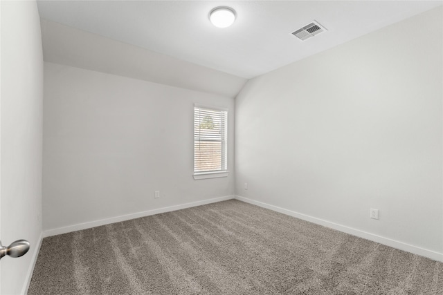 carpeted spare room featuring visible vents, baseboards, and vaulted ceiling