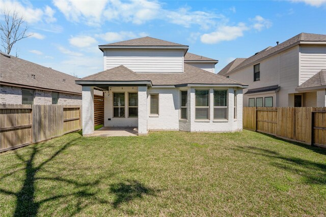 rear view of house featuring brick siding, a lawn, a patio, and a fenced backyard