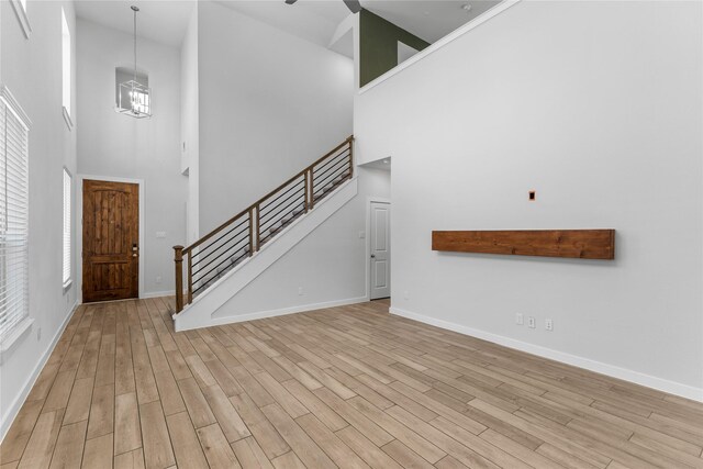 foyer entrance with light wood finished floors, stairway, an inviting chandelier, and baseboards