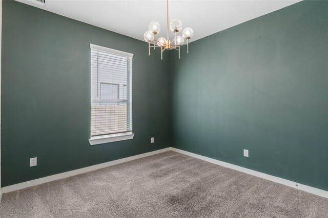 carpeted empty room with baseboards and an inviting chandelier