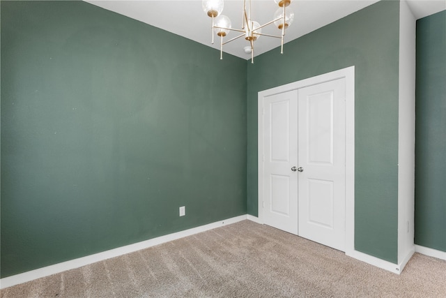 unfurnished bedroom with a closet, baseboards, carpet, and a chandelier