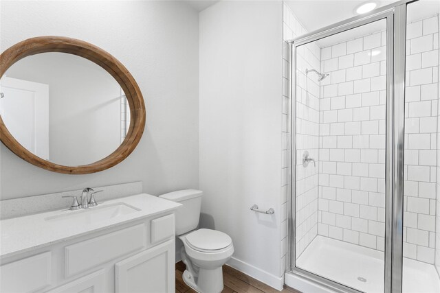 full bath featuring baseboards, toilet, a stall shower, and vanity