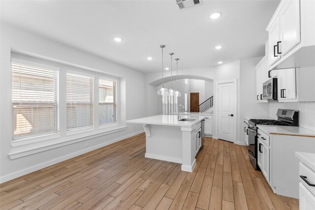 kitchen with visible vents, light countertops, arched walkways, stainless steel appliances, and a sink