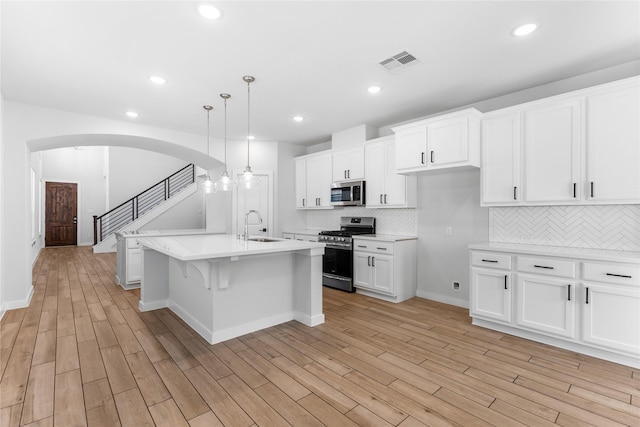 kitchen with visible vents, light wood-style flooring, a sink, light countertops, and appliances with stainless steel finishes