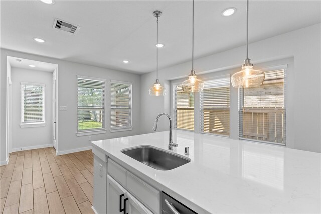 kitchen with a sink, visible vents, light countertops, and light wood finished floors