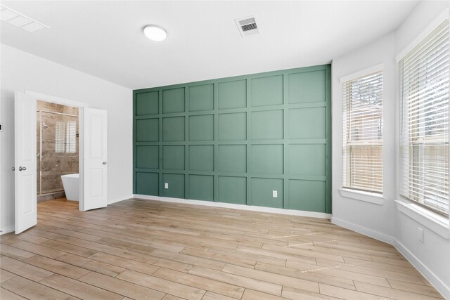 unfurnished bedroom featuring a decorative wall, light wood-style floors, and visible vents