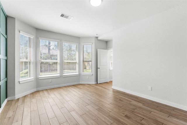 unfurnished room with visible vents, light wood-type flooring, and baseboards