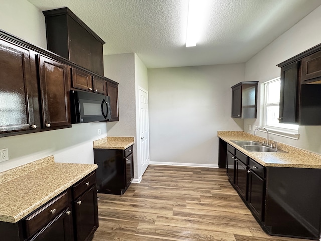 kitchen with wood-type flooring, sink, dark brown cabinets, and a textured ceiling